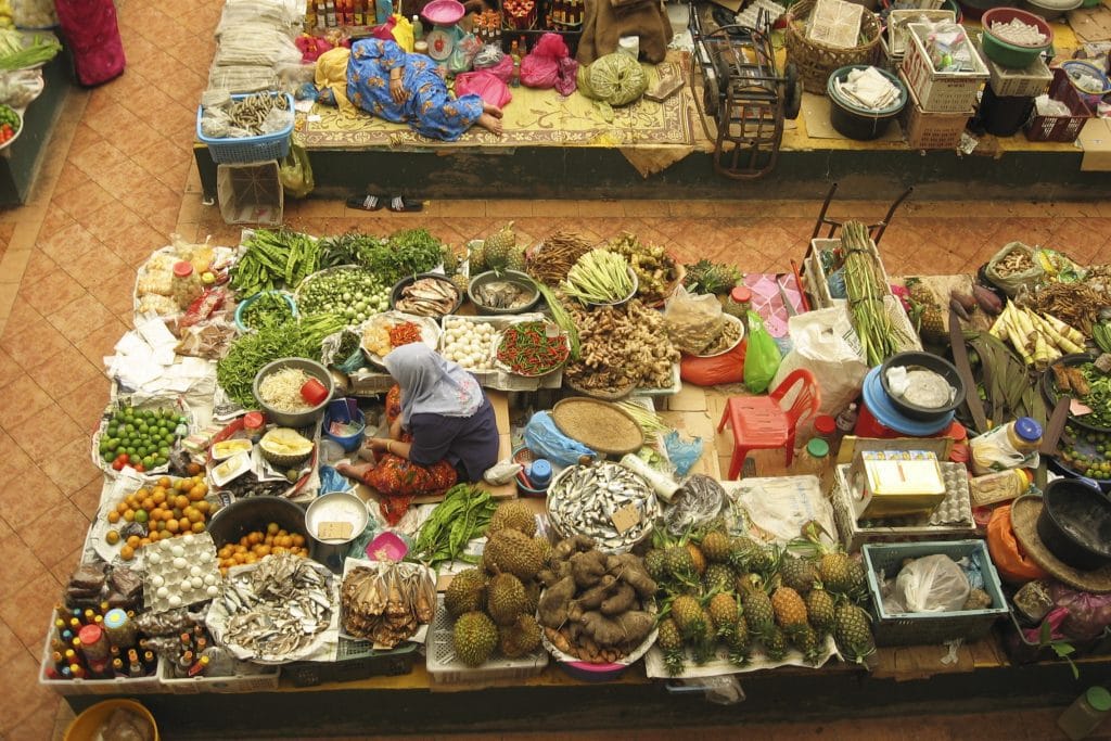 Marktverkoper slaapt op een kraam vol groenten, kruiden en specerijen op de markt van Kota Bharu in Maleisië