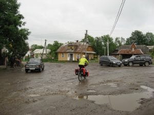 Grijs straatje in Nebyliv, Oekraïne, met verouderde houten huizen, elektriciteitspalen en een paar voorbijgangers onder bewolkte lucht