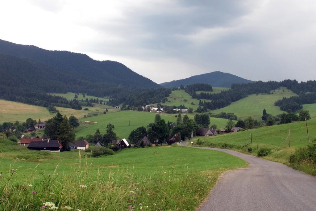 Wijd panorama van een groen bergdal met verspreide boerderijen en beboste heuvels in Veľké Borové in Slowakije