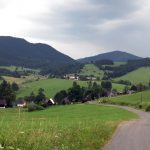 Wijd panorama van een groen bergdal met verspreide boerderijen en beboste heuvels in Veľké Borové in Slowakije