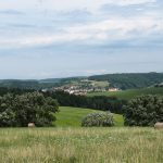 Heuvelachtig landschap met soortenrijke bloemenweiden, hooibalen en een dorpje tussen bossen in de Bílé Karpaty in Tsjechië