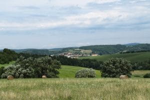 Heuvelachtig landschap met soortenrijke bloemenweiden, hooibalen en een dorpje tussen bossen in de Bílé Karpaty in Tsjechië