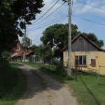 Traditioneel geel boerenhuis met houten bovenbouw langs een onverhard pad in het dorpje Žítková in Tsjechië