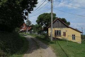 Traditioneel geel boerenhuis met houten bovenbouw langs een onverhard pad in het dorpje Žítková in Tsjechië