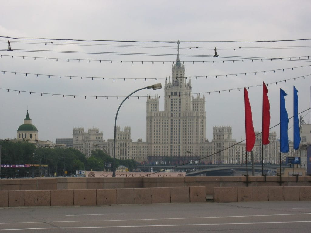 Stalinist wolkenkrabber uit de Sovjet-tijd in Moskou met rode en blauwe feestelijke vlaggen en tramkabels op de voorgrond