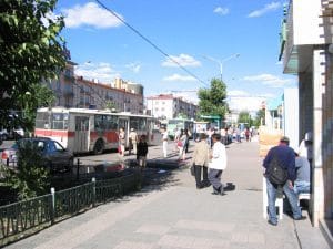 Drukke straat in Ulaanbaatar met een blauwe trolleybus, voetgangers en lage gebouwen onder een blauwe lucht
