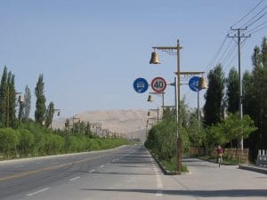 Verkeersbord met 40 km/u limiet en decoratieve bellen op de fietsroute naar de zandduinen van Dunhuang