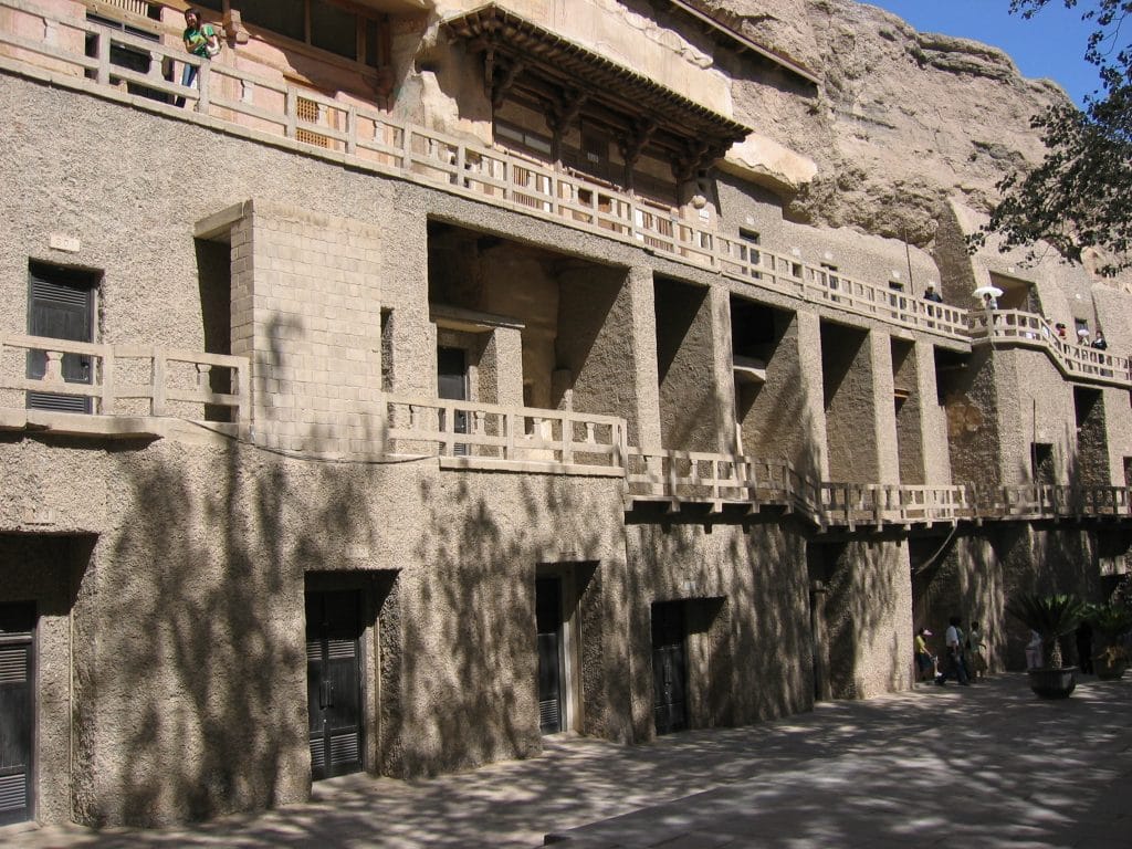 Houten balkons op meerdere niveaus langs de rotswand van de Mogao-grotten bij Dunhuang