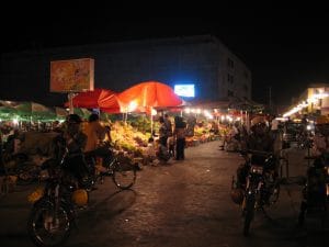 Avondmarkt in Golmud met rode parasols, verlichte kraampjes en fruit op de kramen in het donker