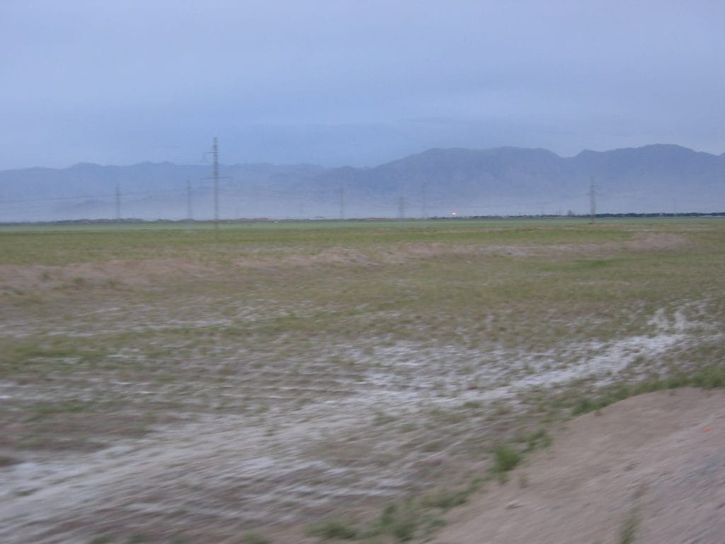 Desolate vlakte met hoogspanningsmasten en mistige bergen in de verte op de route naar Golmud