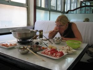 Vrouw eet met eetstokjes van een hotpot in een restaurant in Xining, de Chinese versie van de fondue