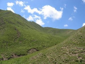Steile groene berghellingen en smalle vallei langs de weg naar Xiahe in de provincie Gansu
