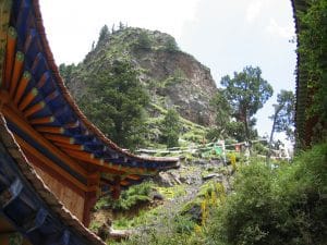 Rotsige bergtop met naaldbomen bij Luqu, gezien vanuit een badkamer met kleurrijke houten omlijsting