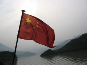 Rode Chinese nationale vlag met vijf gele sterren wapperend in de wind tegen een bleke hemel