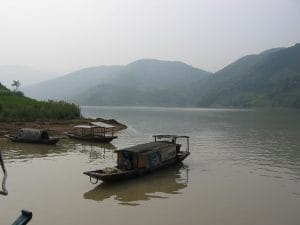 Mistig rivierlanschap langs de Jangtsekiang bij Fengjie met een eenzame boom op de oever en groene heuvels op de achtergrond