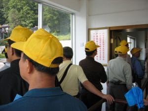 Groep Chinese toeristen met identieke gele petten van achteren gezien bij een bezienswaardigheid in Dali, Yunnan