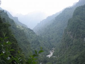 Mistige bergvallei in het Cangshan-gebergte bij Dali, Yunnan, met beboste hellingen die verdwijnen in lage wolken