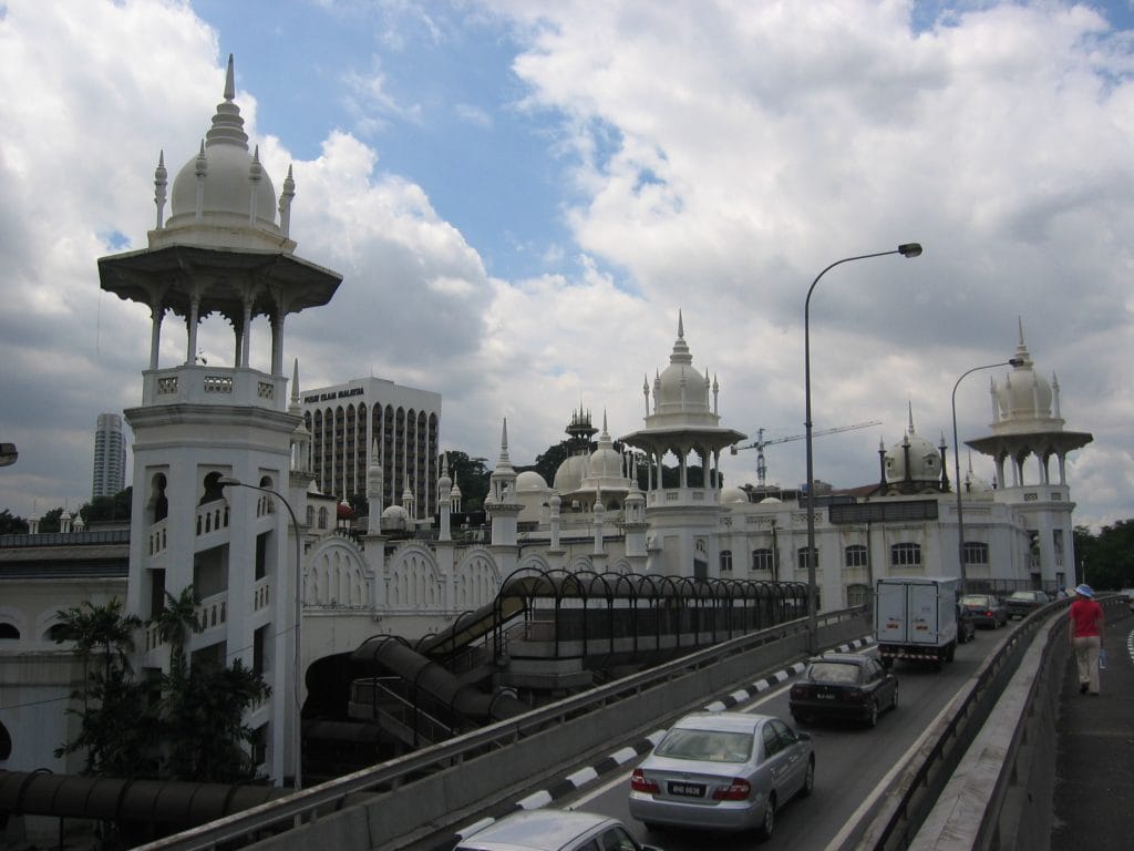 Het historische treinstation van Kuala Lumpur met witte Moors-geïnspireerde koepels en torens tegen een bewolkte lucht