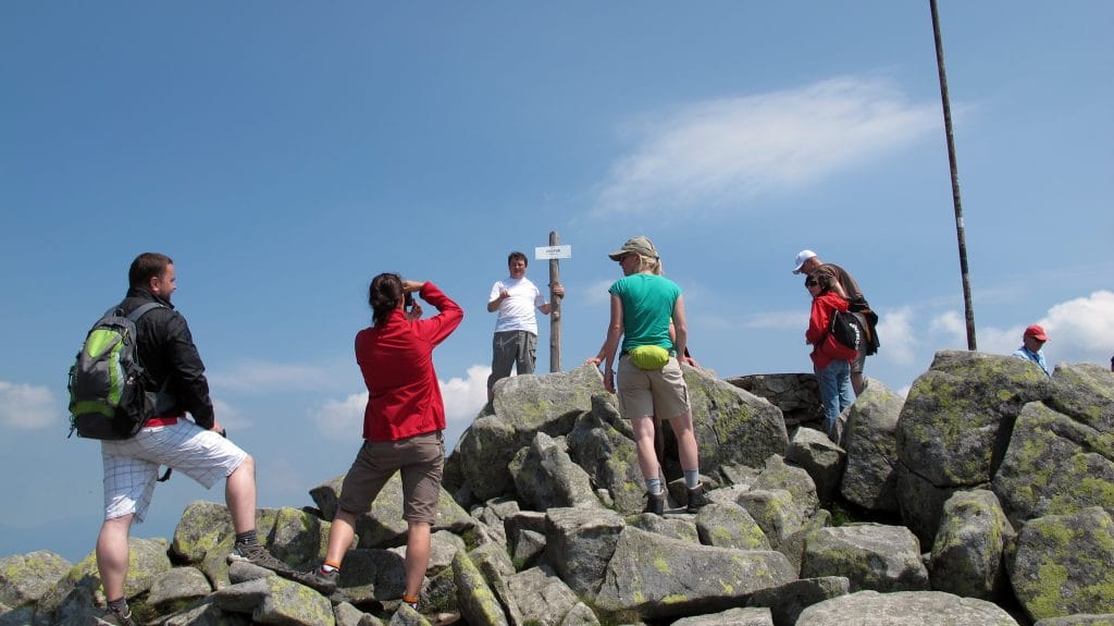 Groep wandelaars op de rotsige top van Mount Chopok (2.024 m) in de Nízke Tatry met wegwijzerpaal, Slowakije