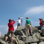 Groep wandelaars op de rotsige top van Mount Chopok (2.024 m) in de Nízke Tatry met wegwijzerpaal, Slowakije