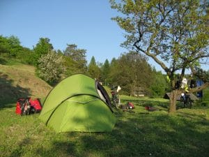 Groene tent op een campingplek bij Ješov in Tsjechië, omgeven door bomen in de zomerzon