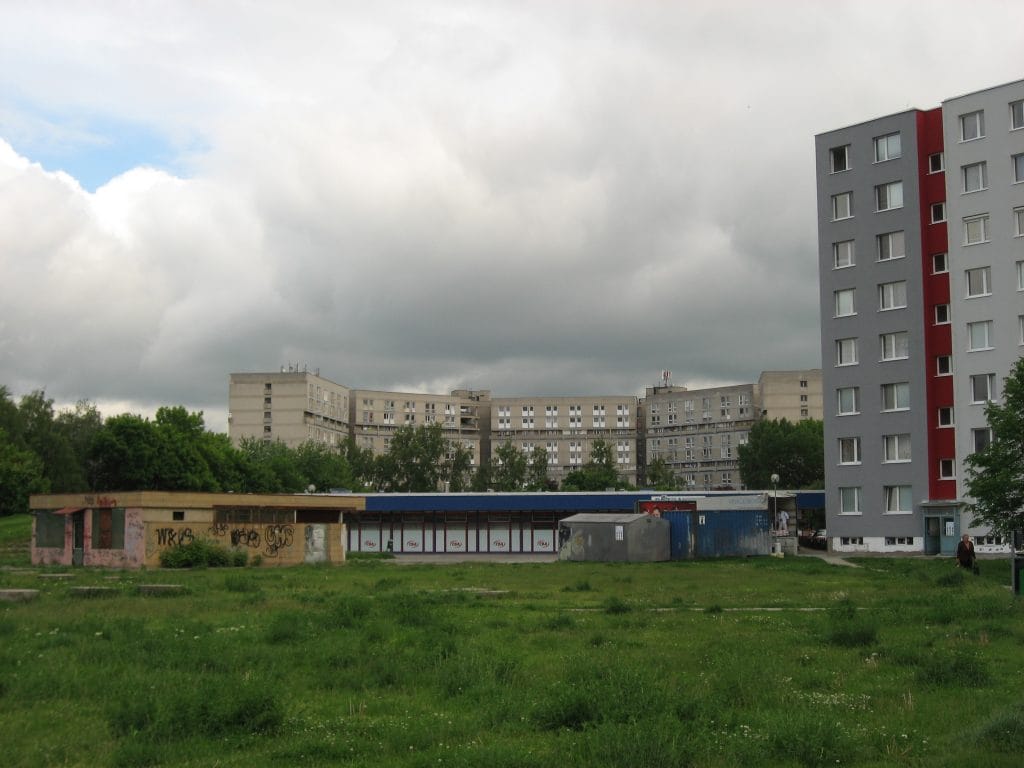 Grijs communistisch flatgebouw met rode accenten in de wijk Vrakuňa in Bratislava, Slowakije, onder een bewolkte lucht