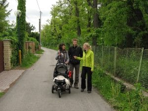 Drie mensen wandelen op een groen boomrijk pad in een woonwijk van Bratislava, Slowakije