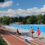 Druk bezocht openlucht thermaal zwembad Termálne kúpalisko in Liptovský Ján gevuld met zwavelhoudend water, omgeven door bomen, Slowakije