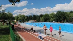 Druk bezocht openlucht thermaal zwembad Termálne kúpalisko in Liptovský Ján gevuld met zwavelhoudend water, omgeven door bomen, Slowakije