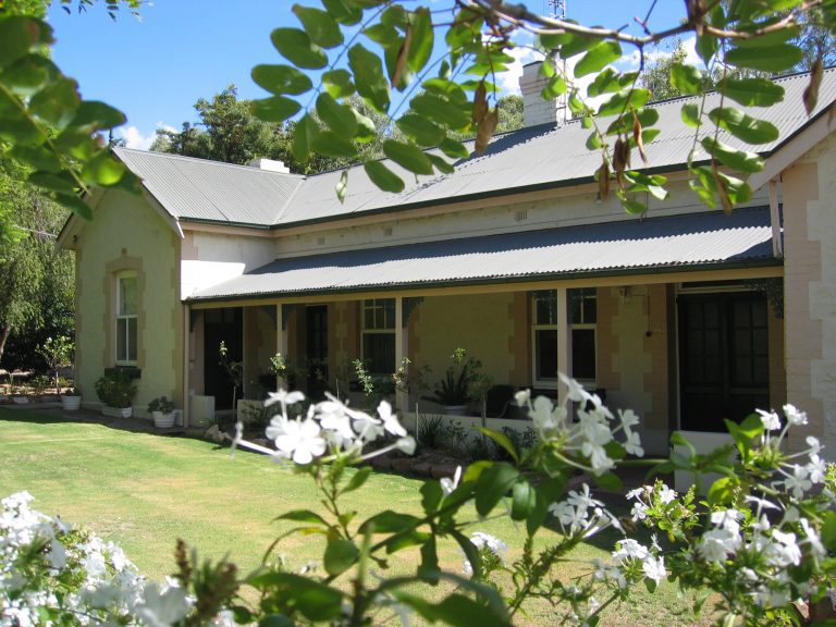 Australisch koloniaal huis met golfplaten dak en brede veranda in Melrose, South Australia, omzoomd door groene bladeren