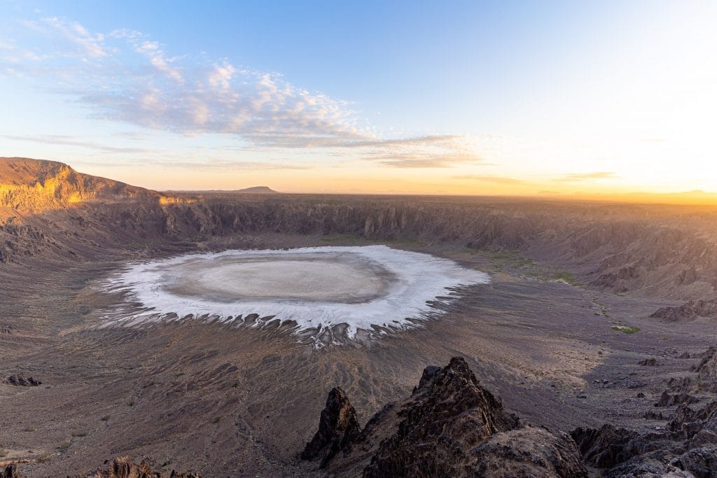 Bovenaanzicht van de Wahba-krater bij Al-Taif, Saoedi-Arabië, met witte zoutvlakte op de bodem en oranje zonsopkomst