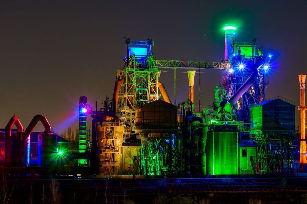 Verlicht voormalig hoogovencomplex in de Landschaftspark Duisburg-Nord bij nacht, met groene en blauwe verlichting