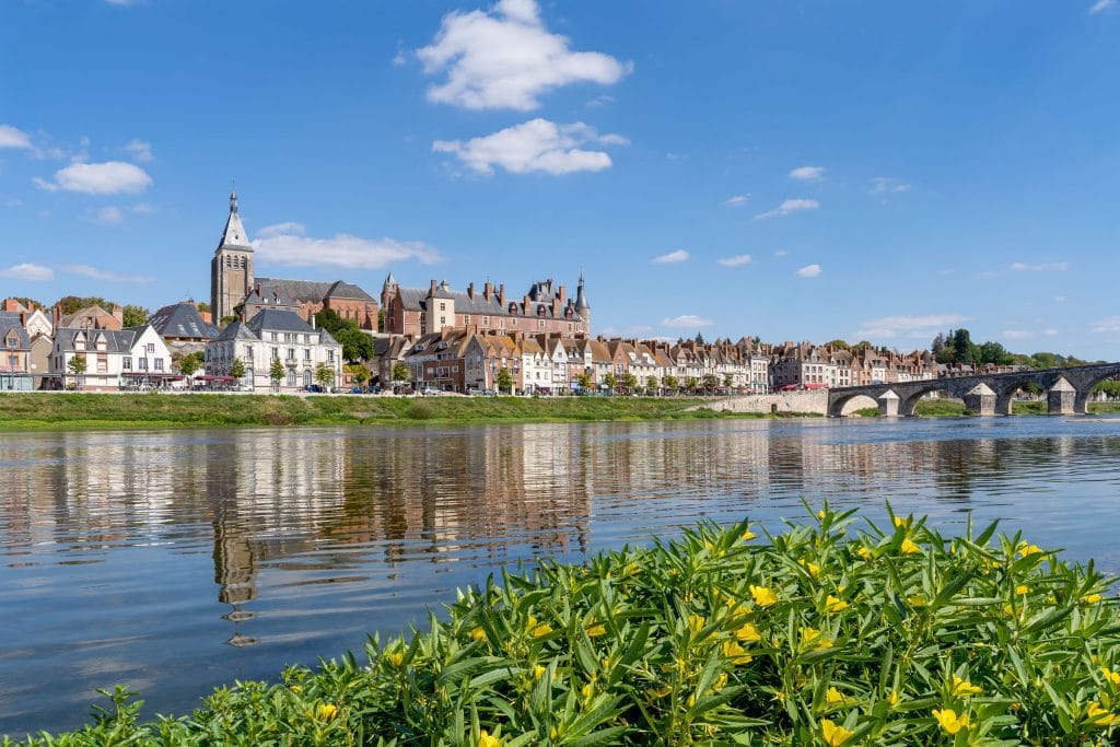 Stadsgezicht van Gien aan de Loire met de kerk, het kasteel en een rij traditionele Franse huizen weerspiegeld in het rustige water