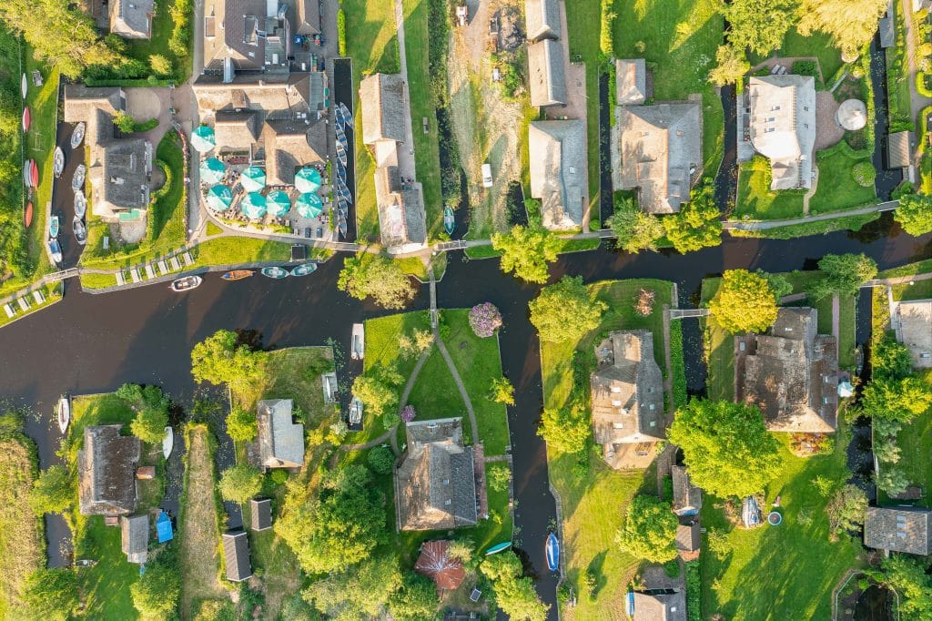 Luchtfoto van Giethoorn met grachten, boten, groene tuinen en rietgedekte huizen gezien van boven