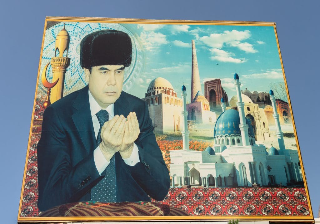 Groot propagandaportret van de Turkmeense president biddend met moskeeën op de achtergrond in Mary, Turkmenistan