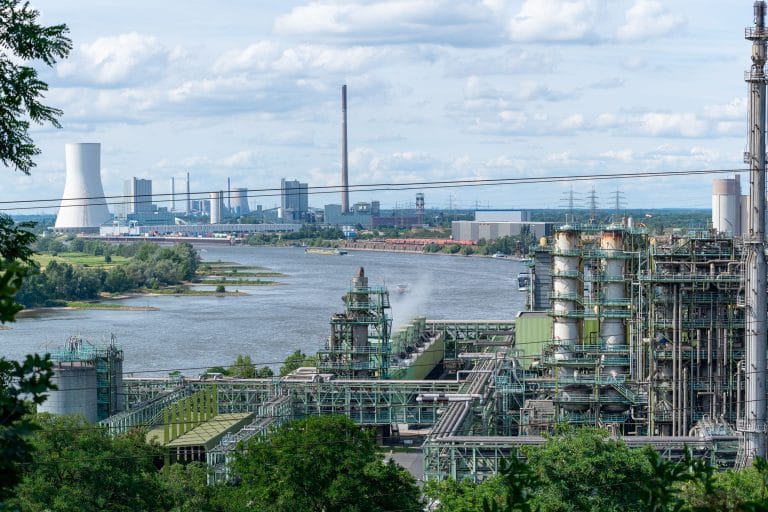 Industrieel landschap in Duisburg met een chemische fabriek op de voorgrond en staalwerk met koeltorens aan de overkant van de Rijn