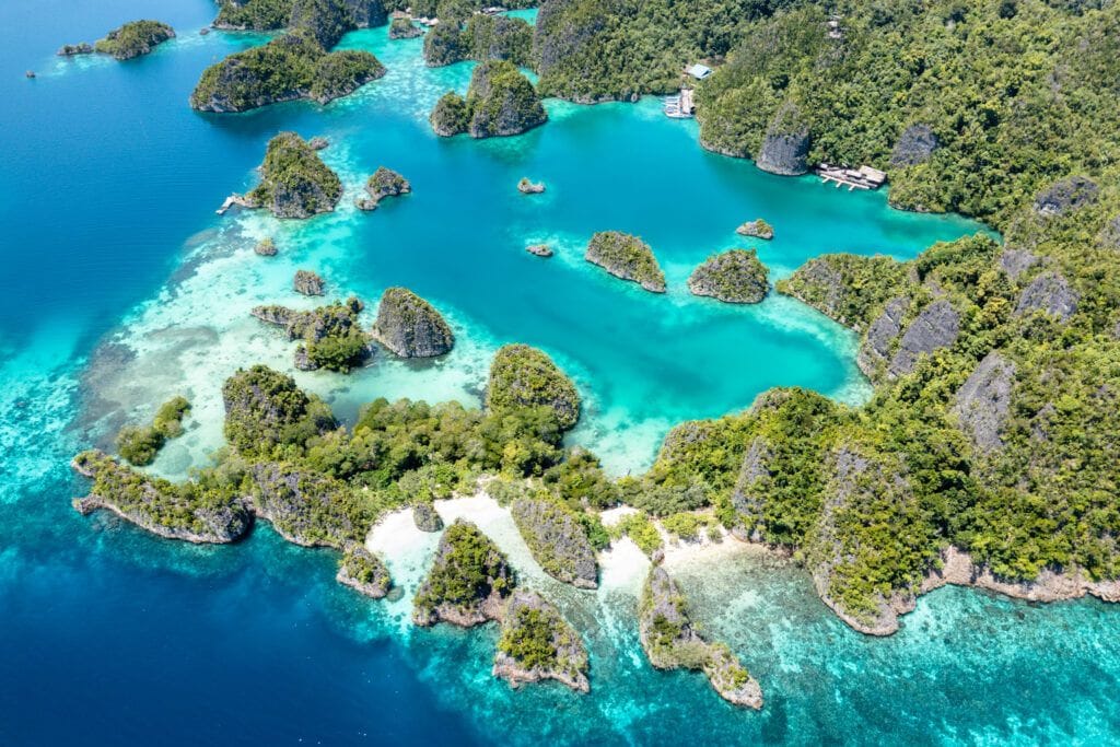 Luchtfoto van de karakteristieke karst-eilandjes van Raja Ampat in turkoois water, het iconische vergezicht van dit Indonesische eilandengebied