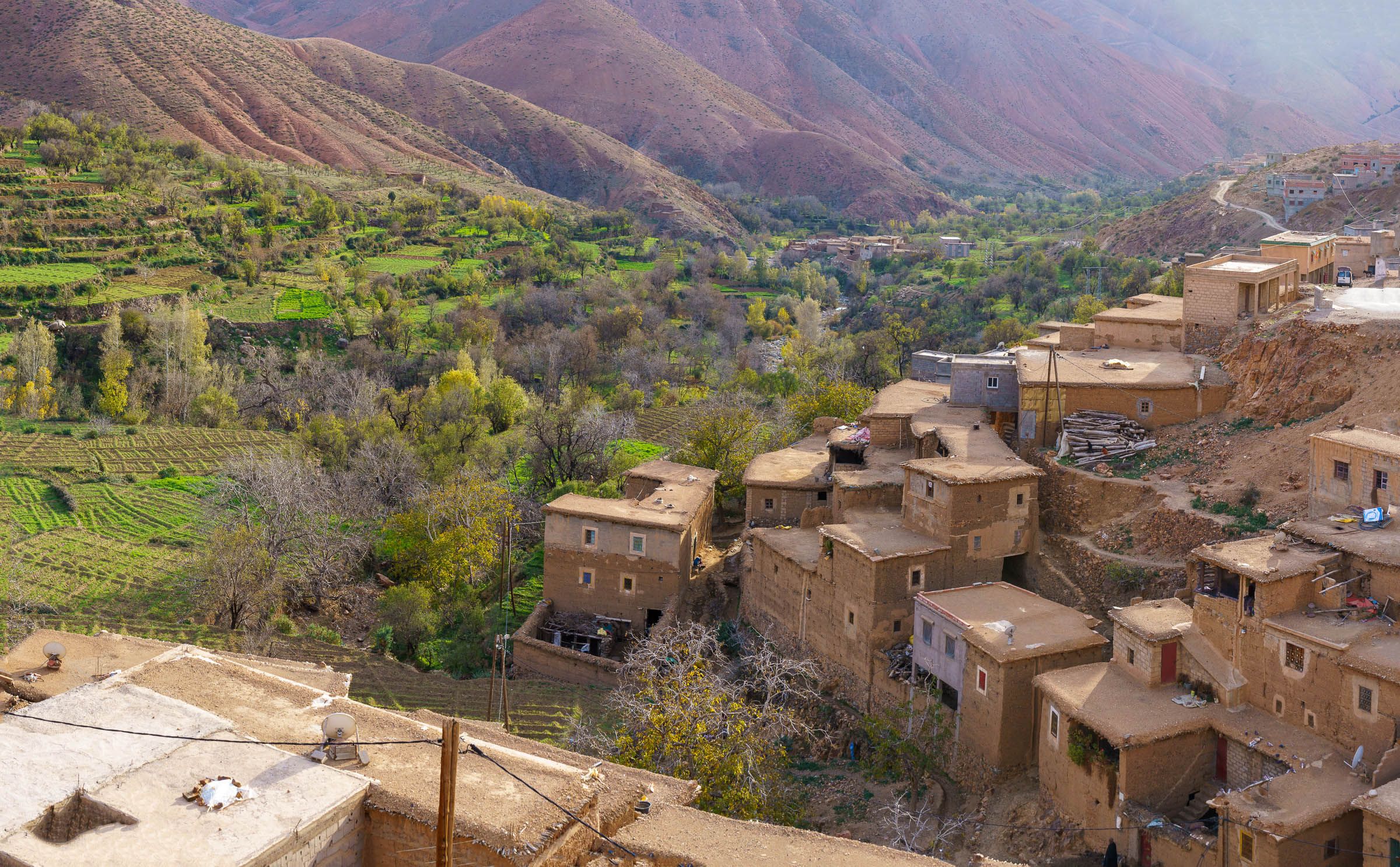 Lemen huizen en groene akkers tegen een bergachtige achtergrond in Marokko.