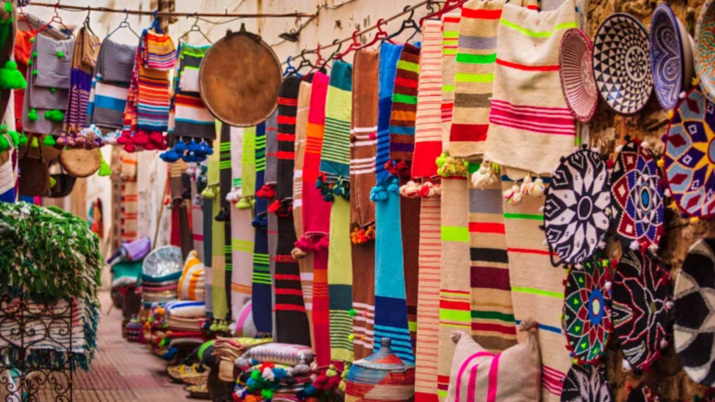 Kleurrijke geweven stoffen, sjaals met pompons en decoratieve manden hangen aan een marktkraam in Senegal