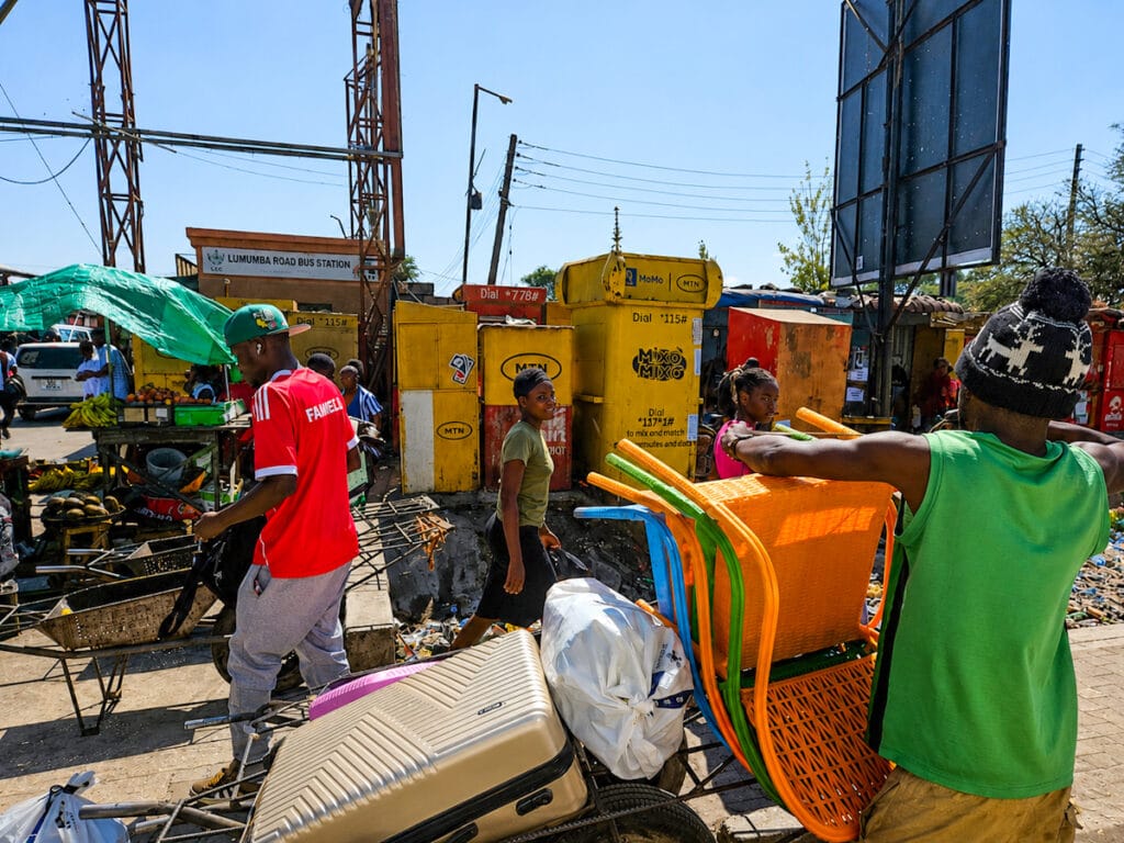 Drukte met handkarren en koffers bij het busstation in Lusaka