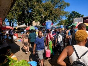 Drukke menigte met verkopers en klanten tussen kleurrijke parasols en marktstalletjes op een buitenmarkt in Afrika