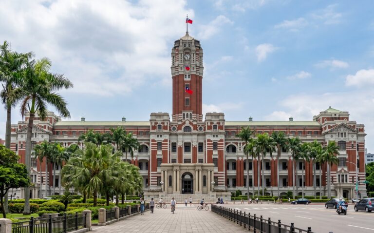 Koloniaal regeringsgebouw in Japans-keizerlijke stijl in Taipei met rode baksteen, witte banden, een centrale toren en palmen ervoor