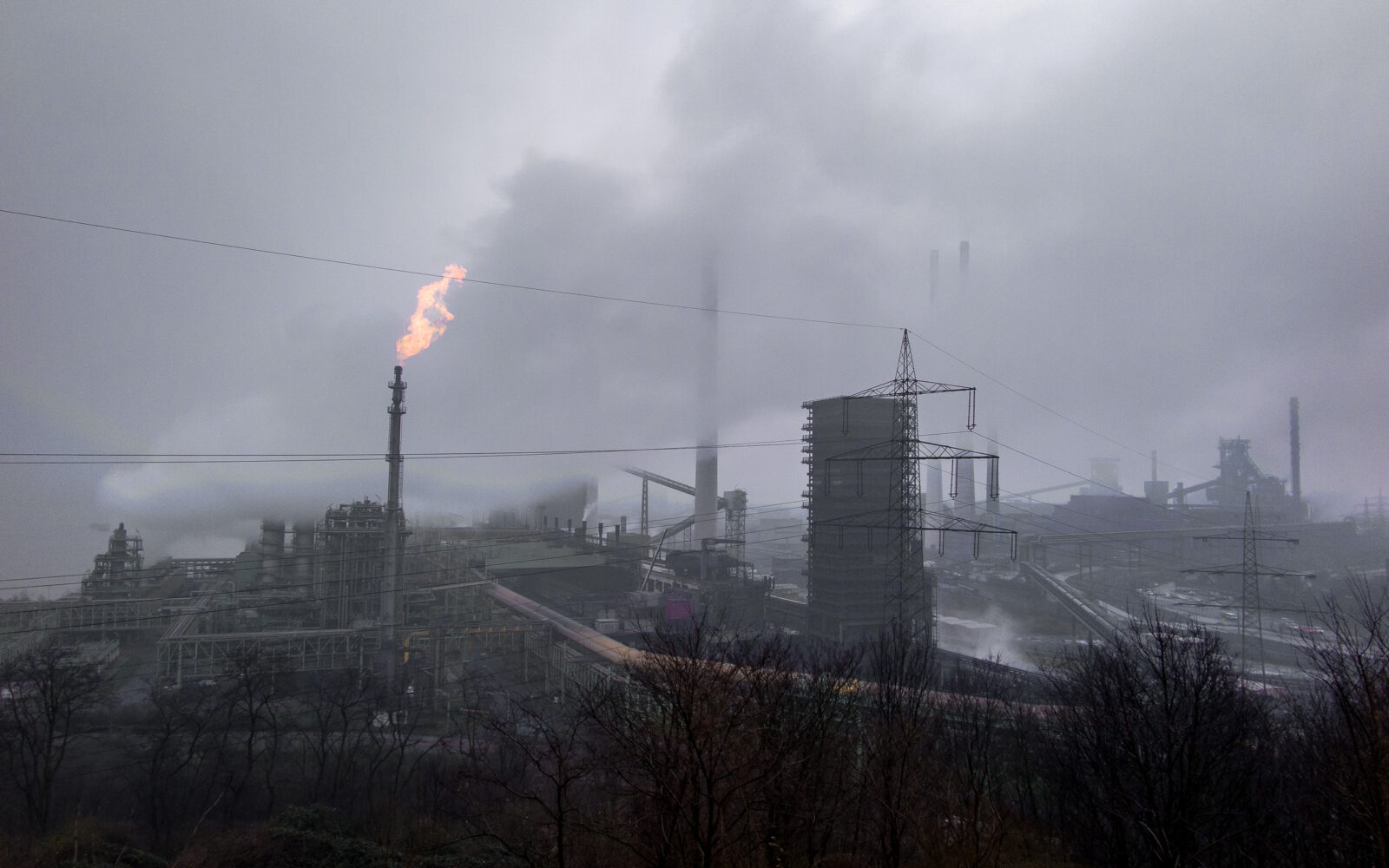 Vlammen boven de staalfabriek in de mist, Duisburg