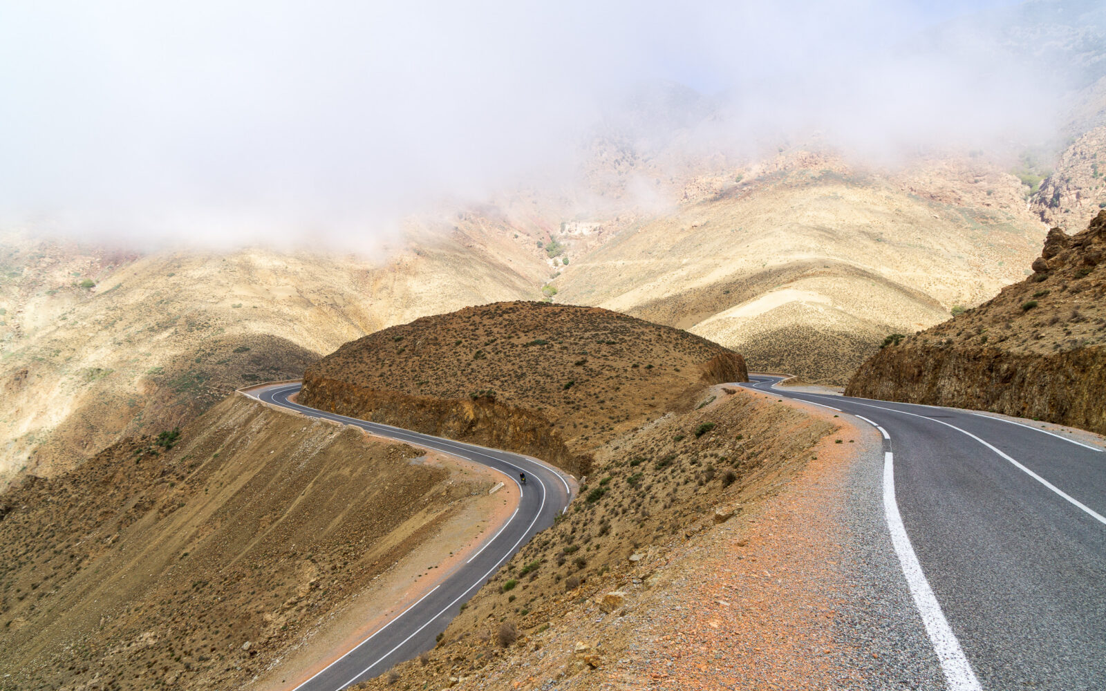 Winding mountain road disappears into the clouds