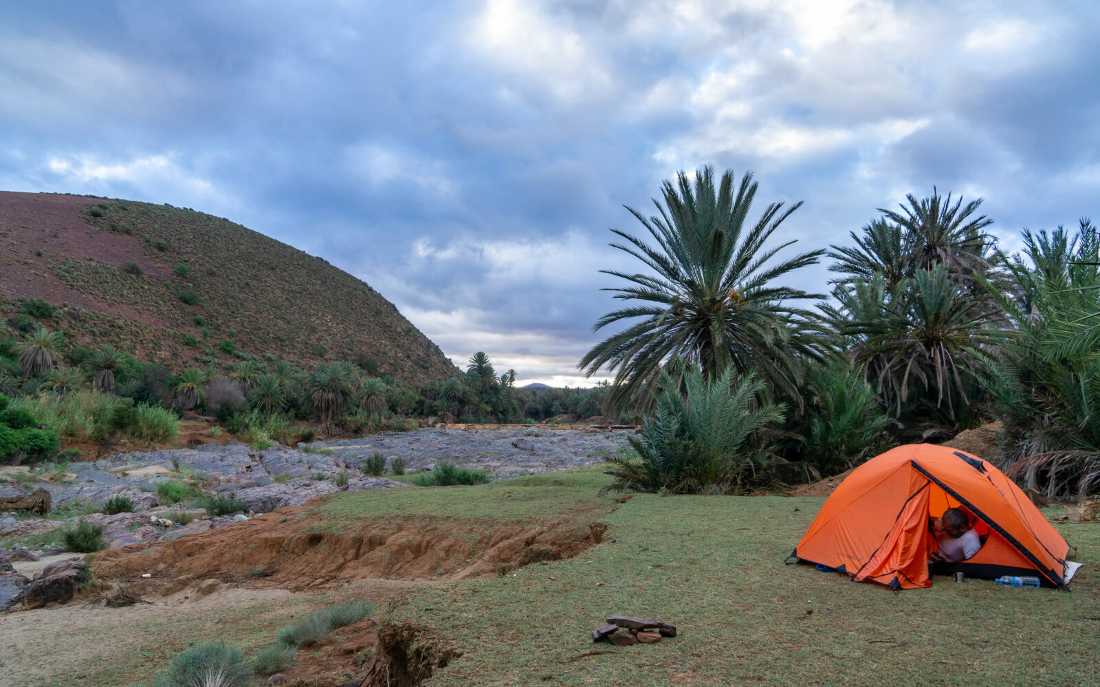 Orange tent set up in a desert oasis