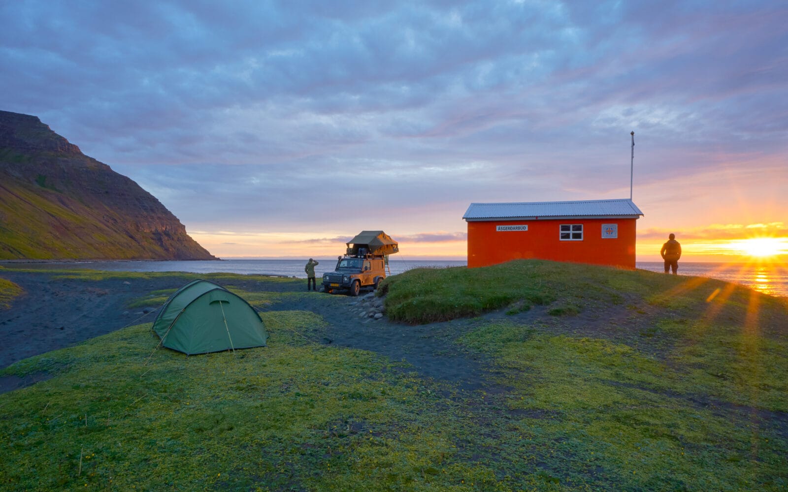 De zon zakt in zee achter het kamp in Skálavík bij Bolungarvík