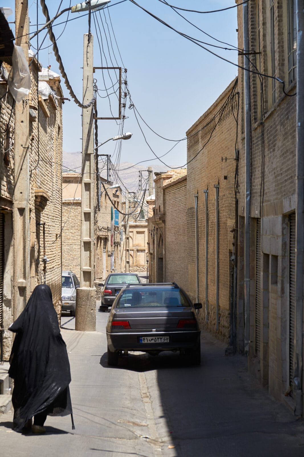 Man loopt door een zonnige steeg in Shiraz
