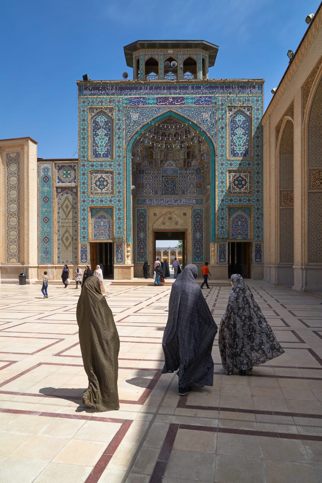 Vrouwen steken de binnenhof van het Shah Cheragh-mausoleum over in Shiraz