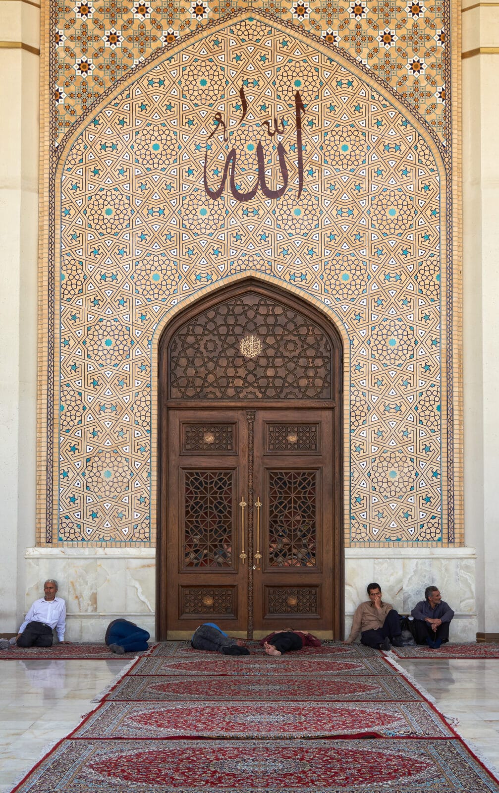 Rustende bezoekers onder het tegelwerk van Shah Cheragh in Shiraz