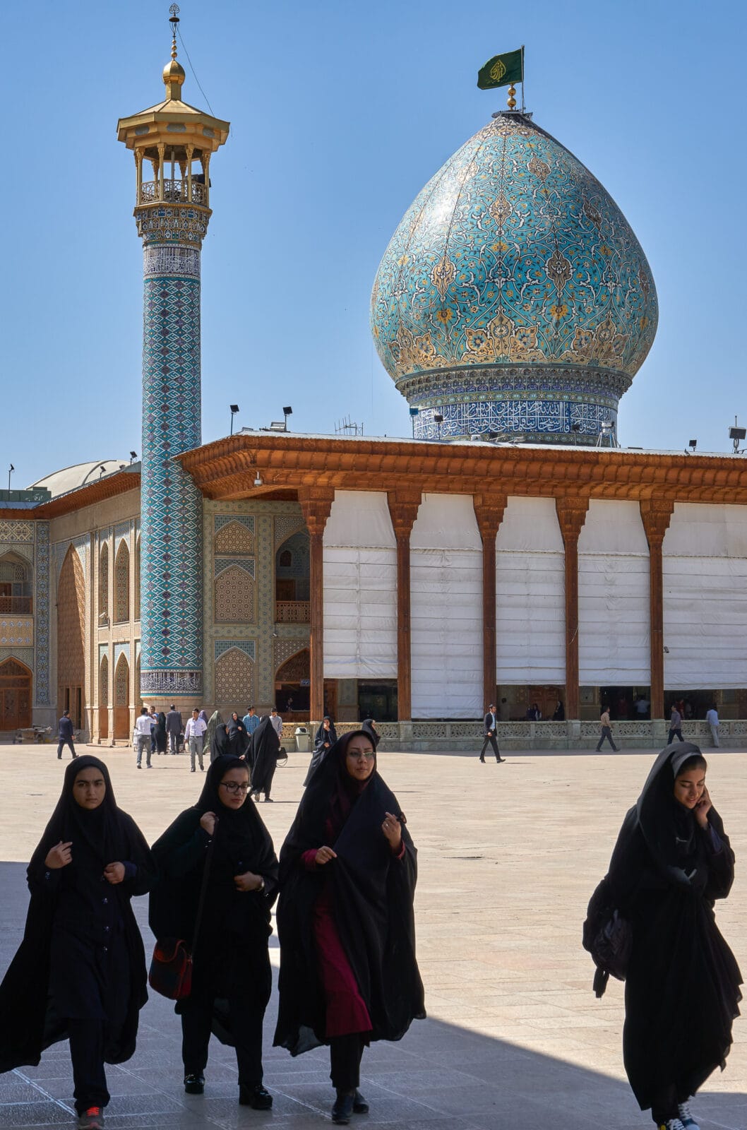 Vrouwen lopen langs de blauwe koepel van Shah Cheragh in Shiraz